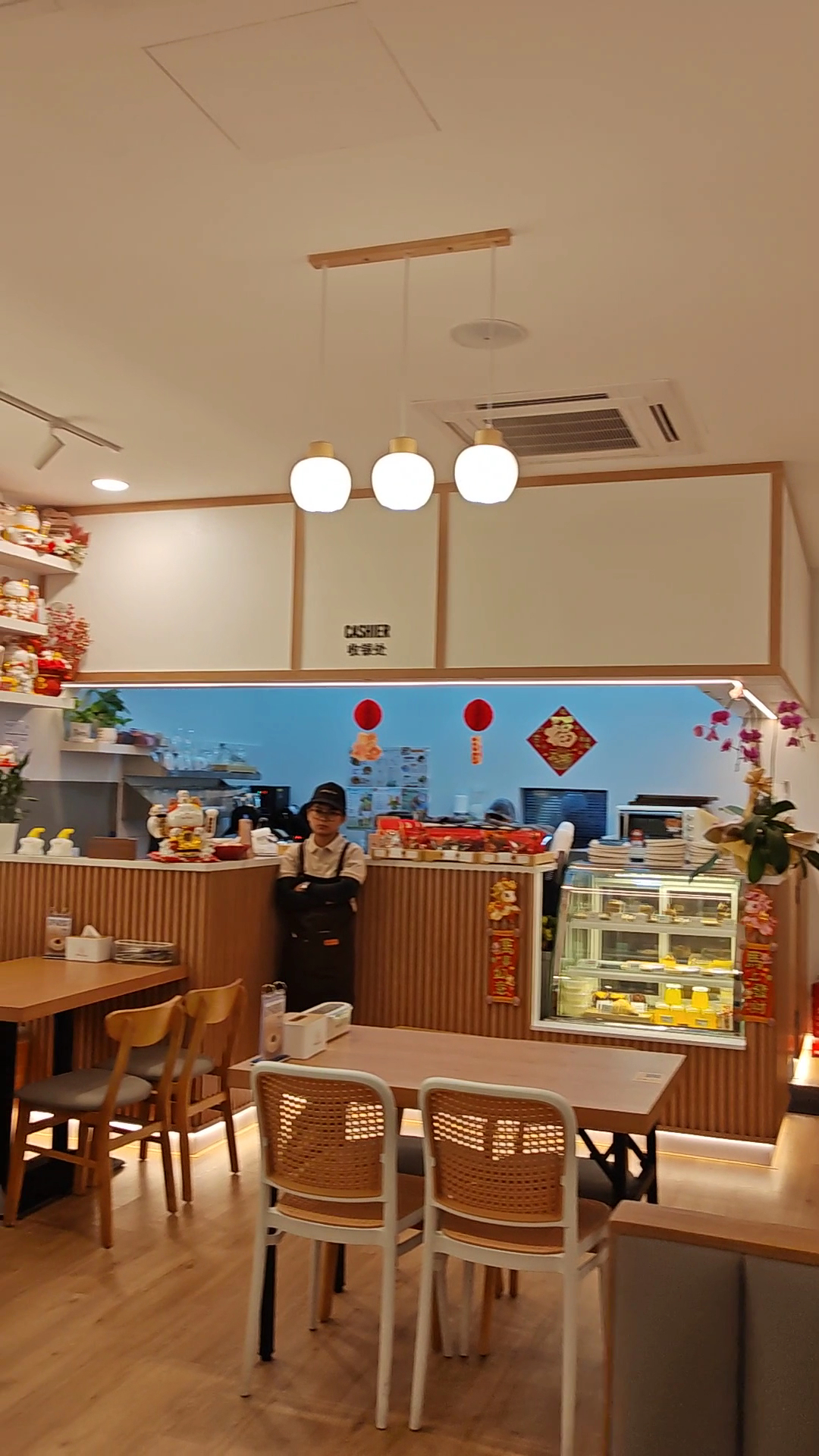 Inside Astarry Cafe — light oak tables, rattan chairs and the cake display by the counter